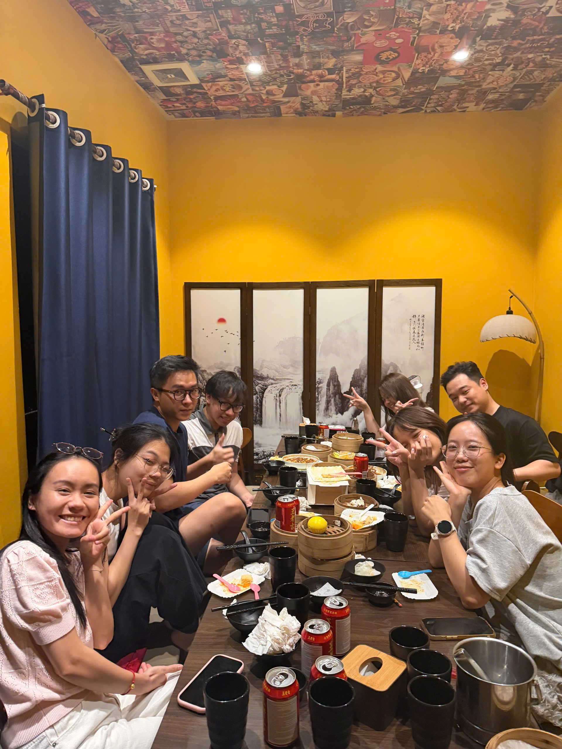 Mọi người quây quần quanh bàn ăn và cười với máy ảnh