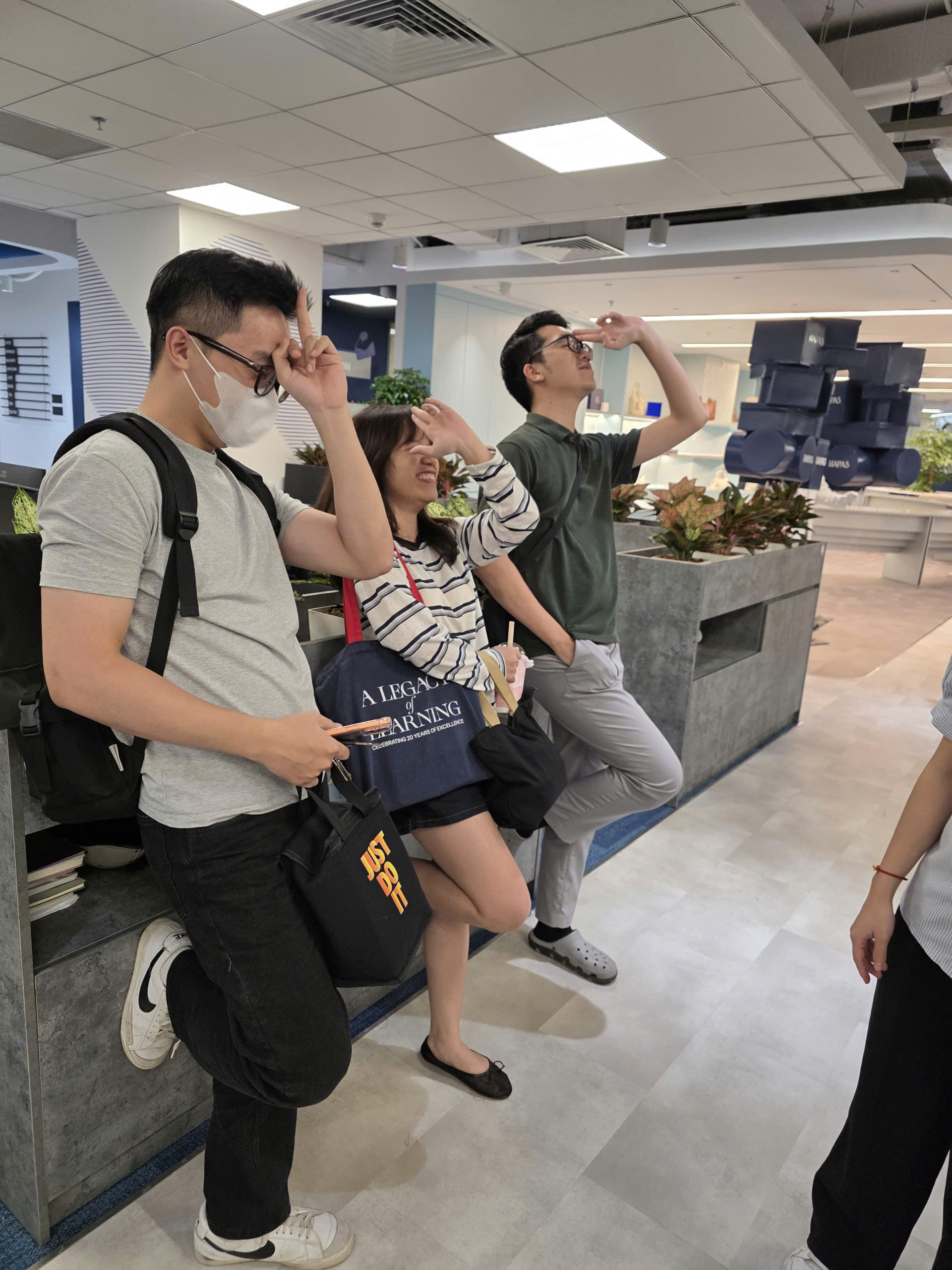 Ba thành viên tạo dáng vui cạnh nhau trong không gian văn phòng